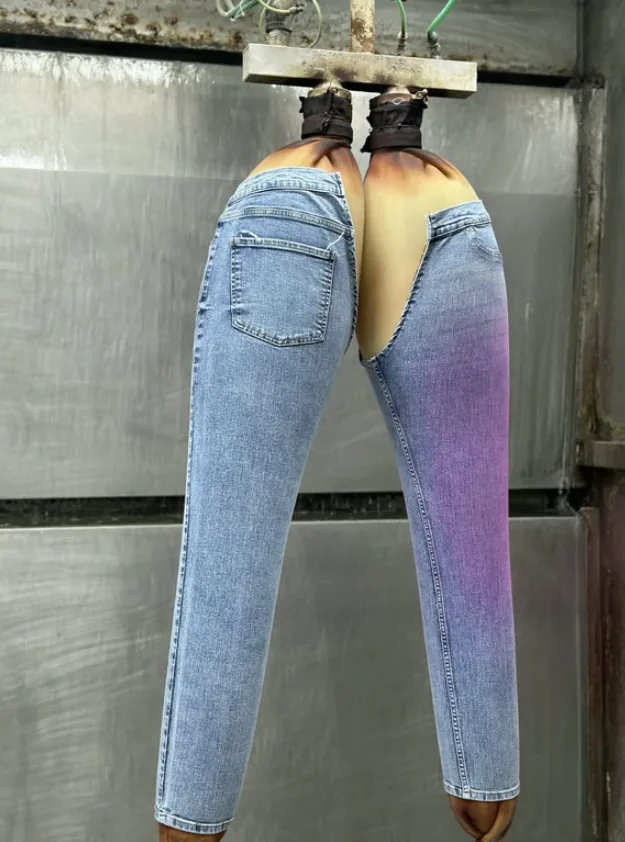 Jeans on a finishing rig with a sprayed ombré tint